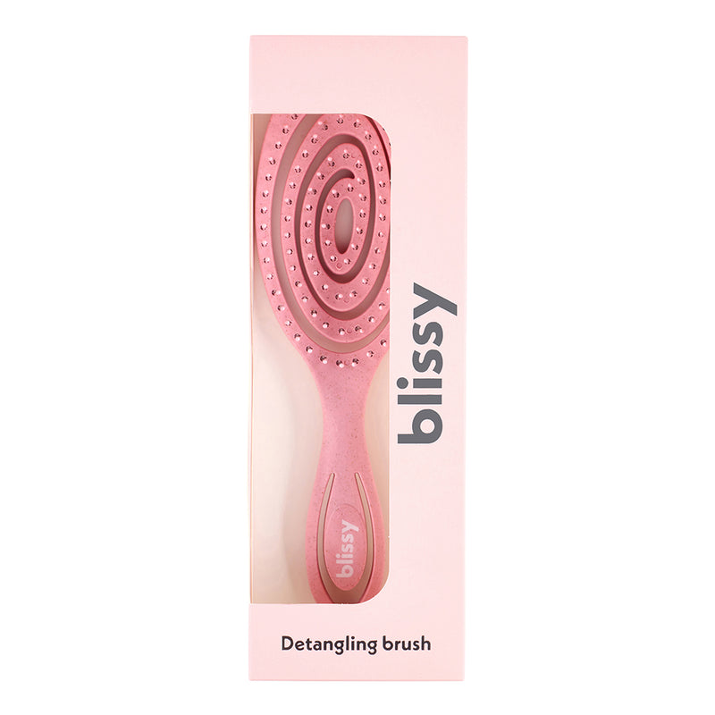 Pink detangling brush with packaging on a white background